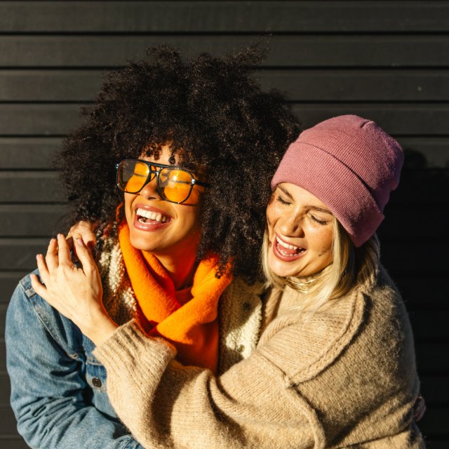Two friends laughing and holding on to each other